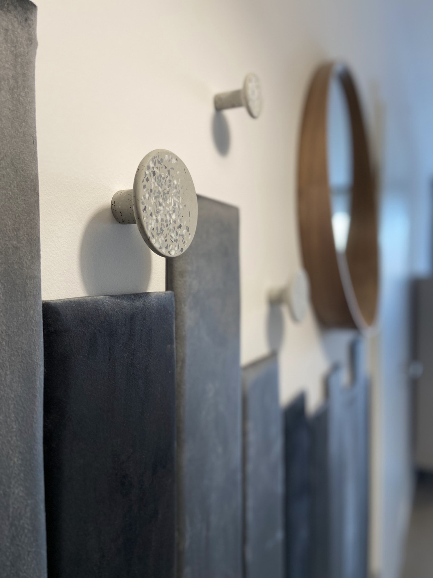 Terrazzo mintás kerek fogasok az előszoba antracit bársony falpanelén